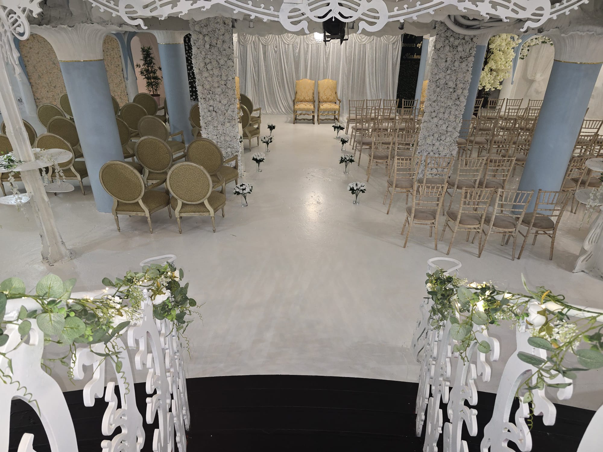 Wide view of the Opulent @ 35 Liverpool ballroom dressed for a wedding with gold drapery, white roses and pale blue Art Nouveau arches inside the Grade II listed Liverpool city-centre venue