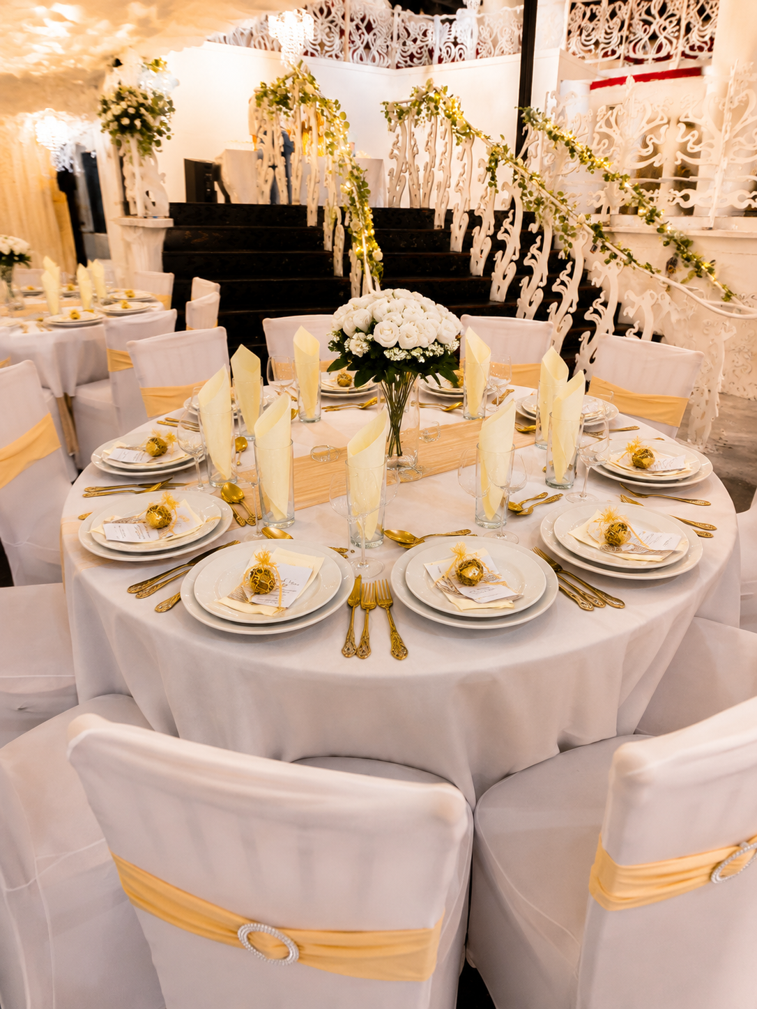 Civil wedding reception at Opulent @ 35 Liverpool — sweeping staircase entrance with round banquet tables, gold sashes and white florals beneath the Art Nouveau ceiling